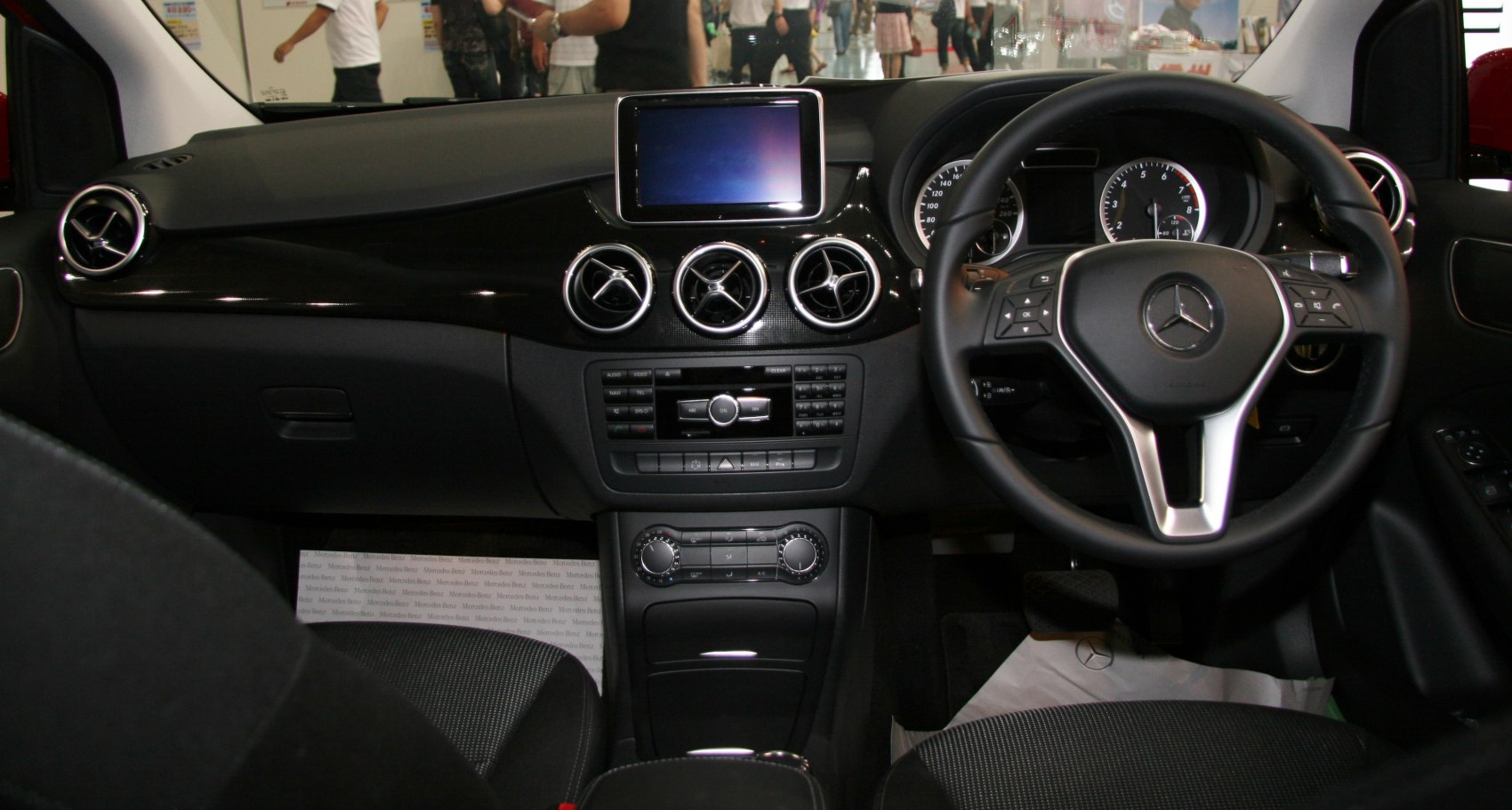 Dashboard with round air vents and steering wheel with controls in compact car interior