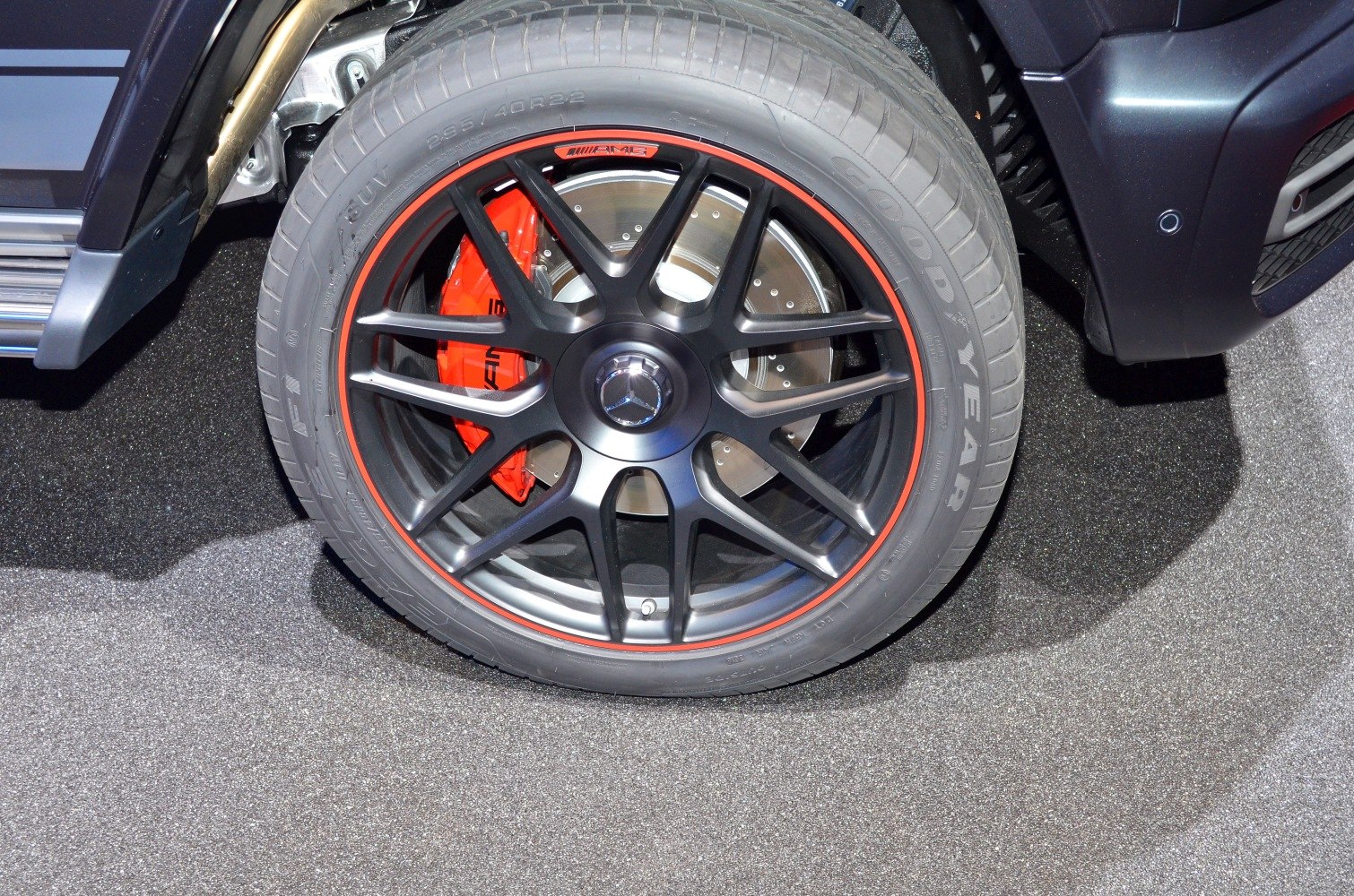 Black AMG wheel rim with red brake caliper and Goodyear tire