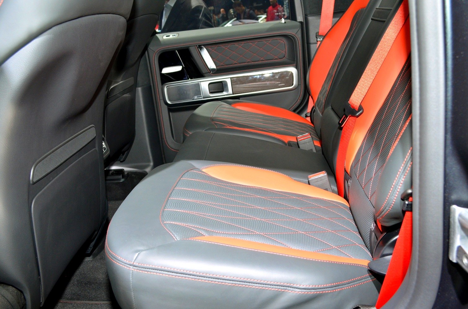 Rear leather seats with red stitching and orange seatbelts in luxury SUV interior