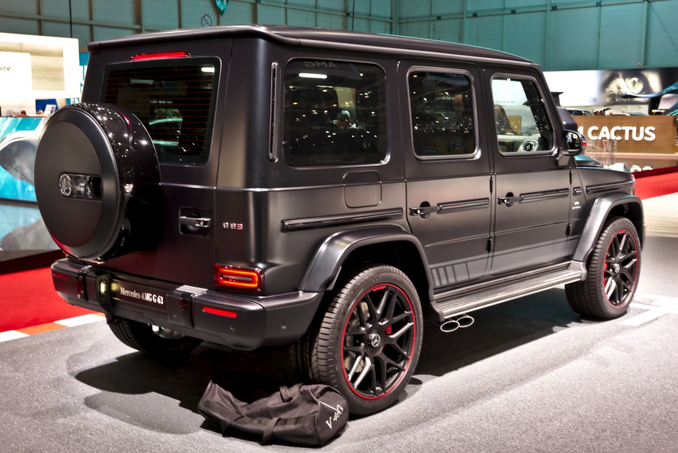 Matte black luxury SUV rear with custom wheels and side exhaust pipes.