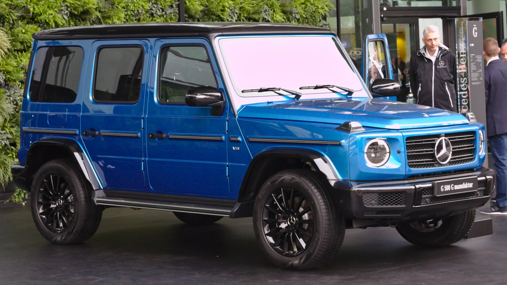 Blue SUV with black wheels and round LED headlights front side view