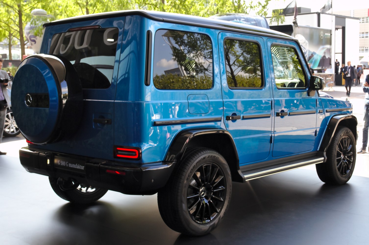 Rear and side profile of blue SUV with spare tire cover and black wheels