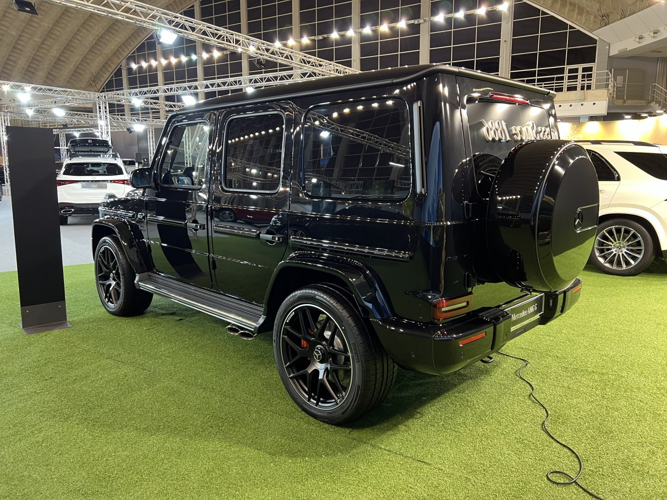 Black SUV, side exhaust pipes, rear spare wheel cover, multi-spoke wheels.
