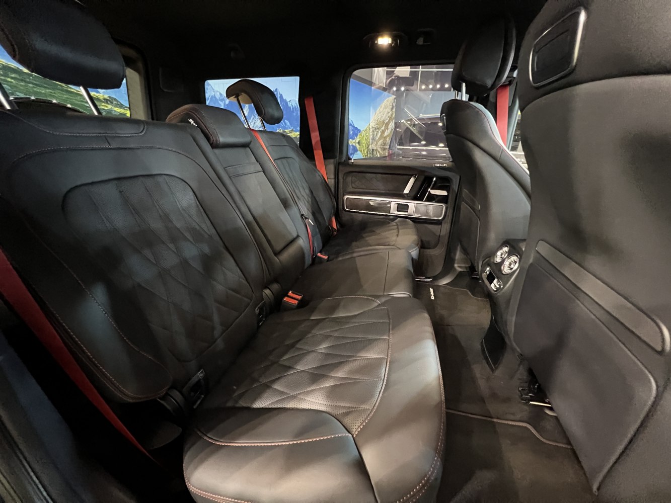 Black leather rear seats with diamond stitching and red seatbelts in a spacious interior