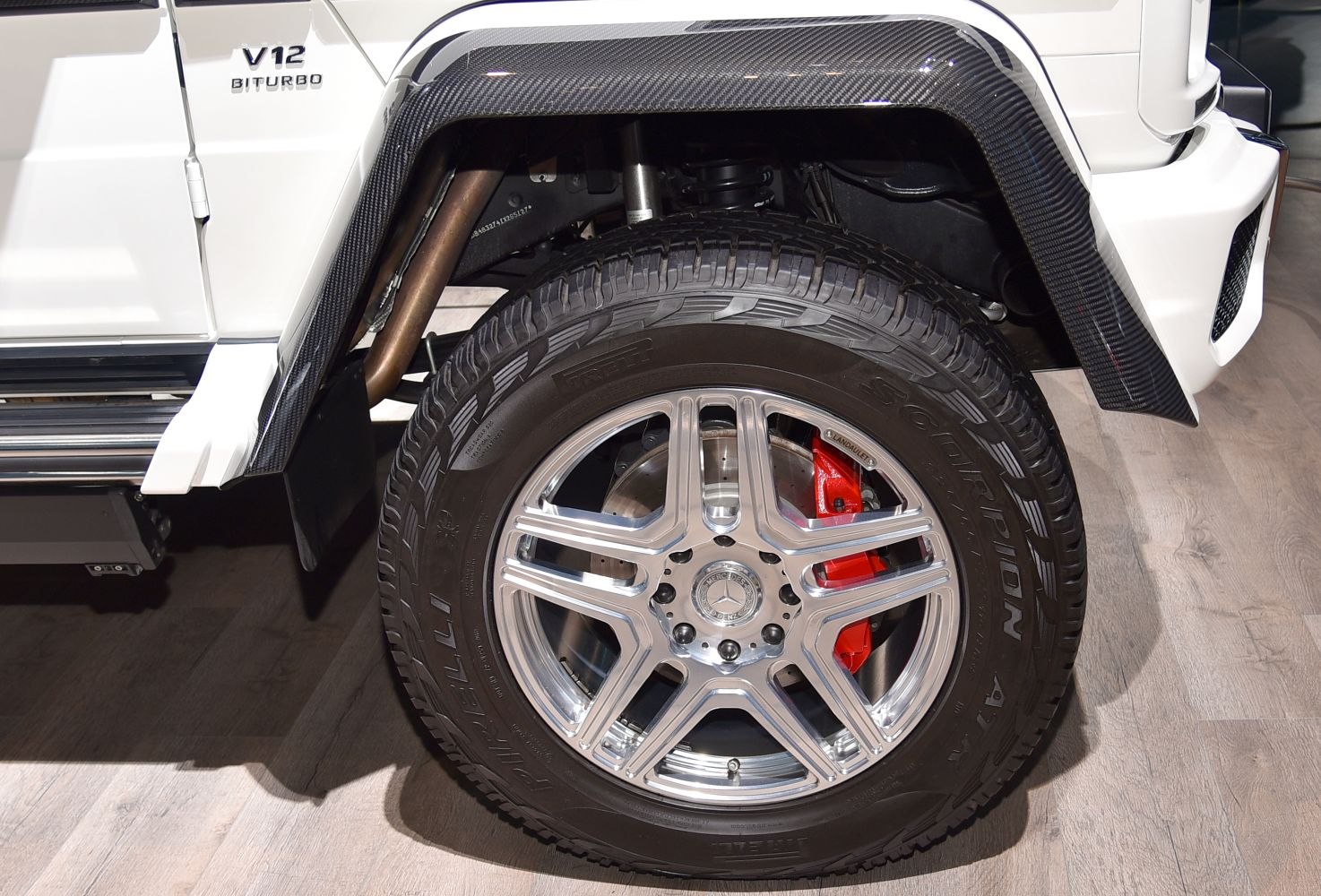 Close-up of wheel, tire, carbon fiber fender, and V12 Biturbo badge