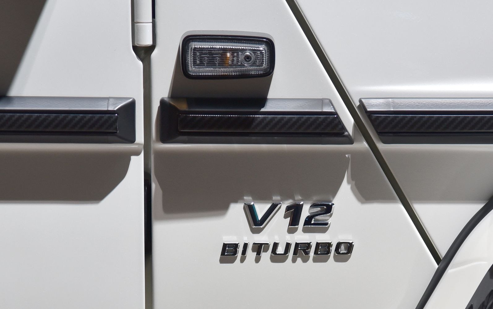 Close-up of V12 Biturbo engine badge on a white SUV door