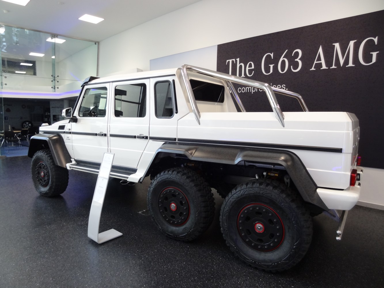 White 6x6 off-road vehicle with six large tires and extended cargo bed