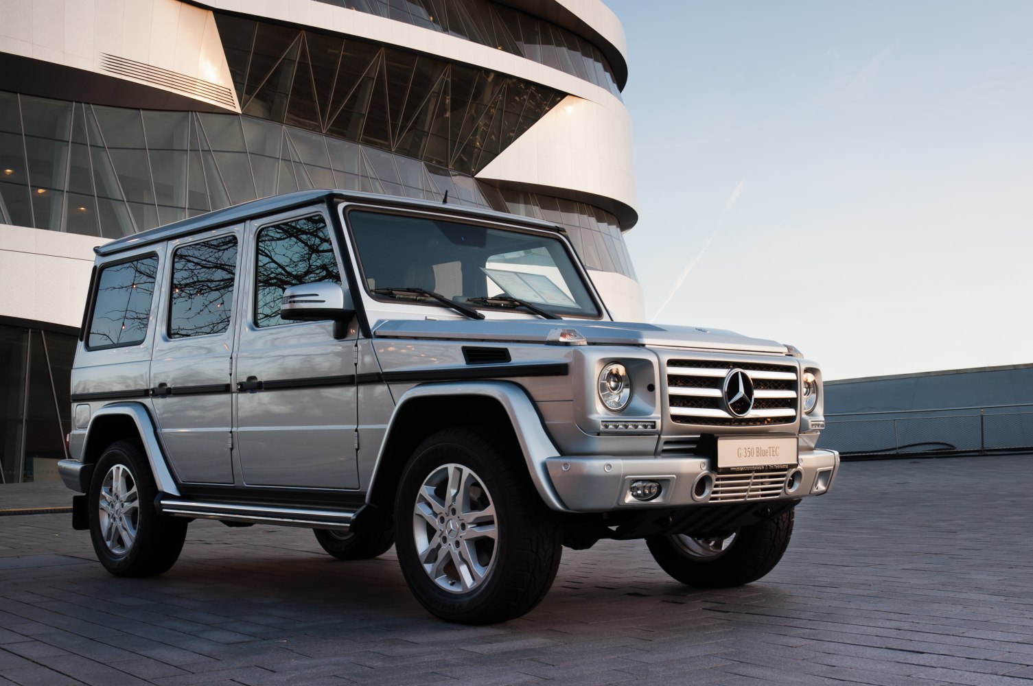 Front side view of silver SUV with boxy design and prominent grille