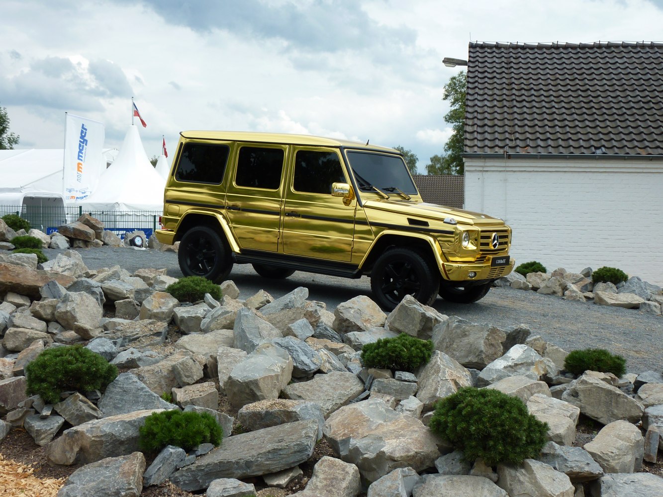 Golden long-body SUV with black wheels on rocky terrain