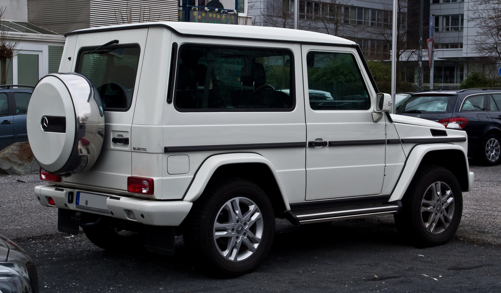 Rear side view of white SUV with spare wheel cover and angular design.