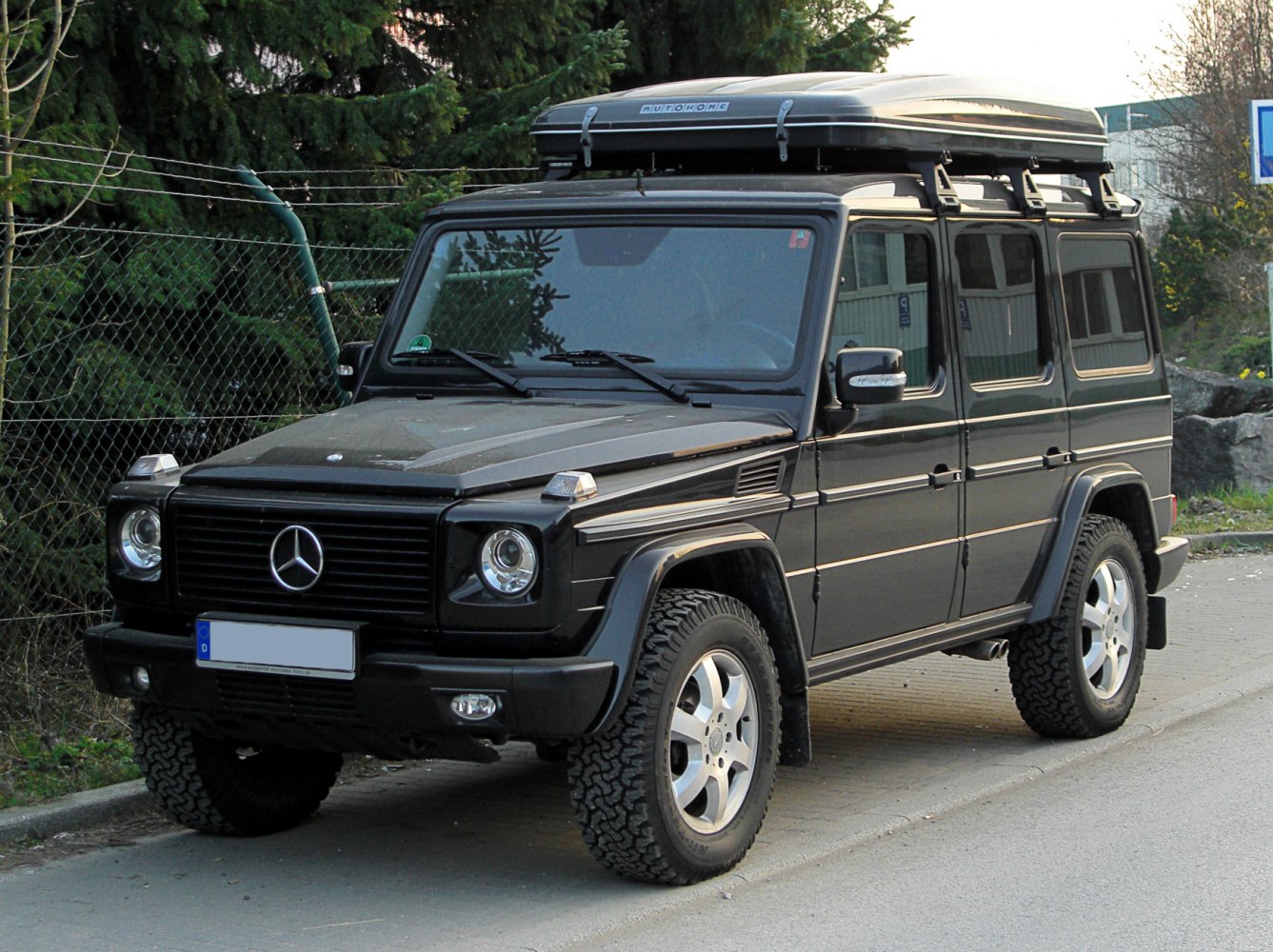 Black off-road SUV with roof cargo box and rugged tires