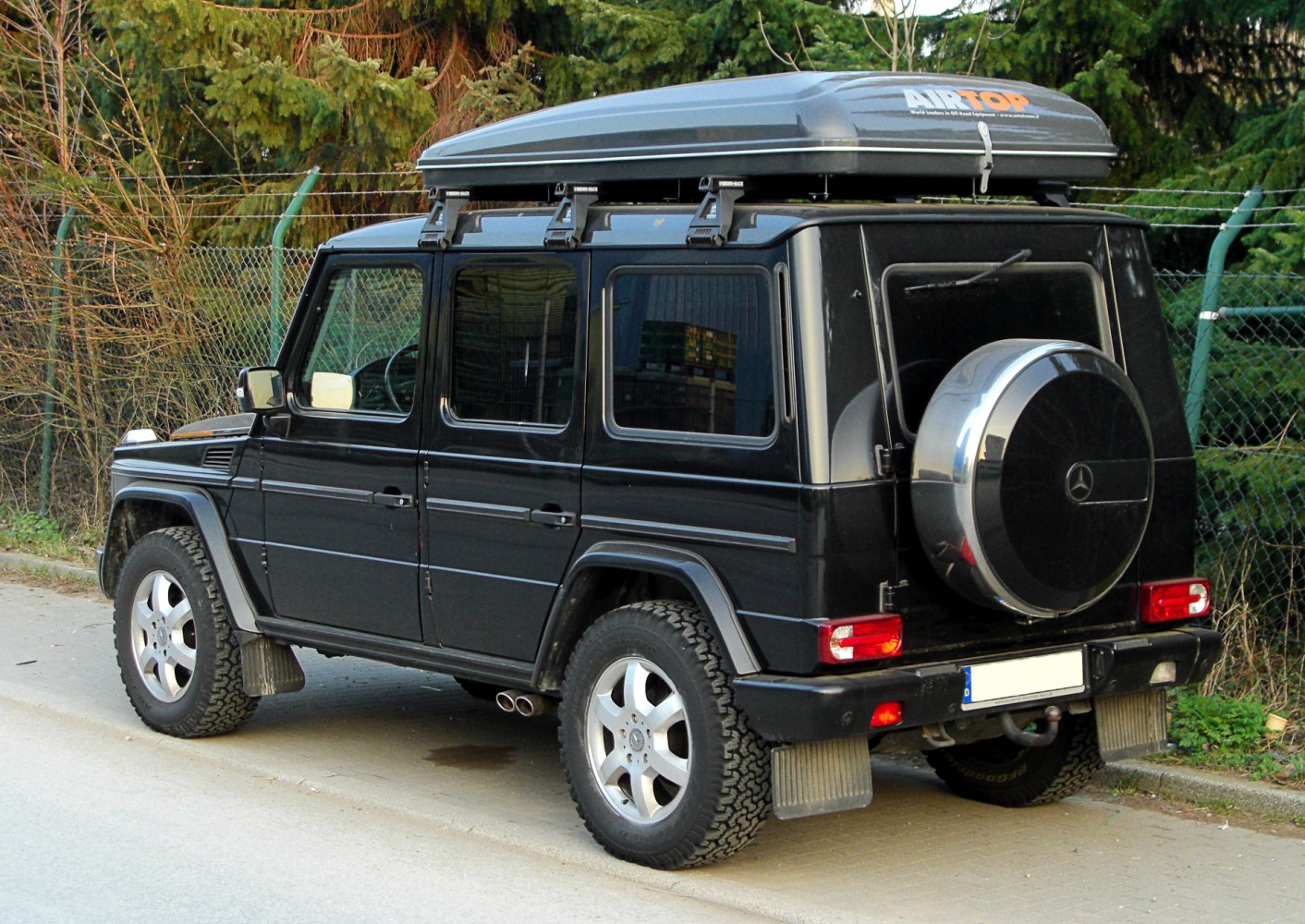 Black long-wheelbase SUV with roof cargo box and spare wheel cover