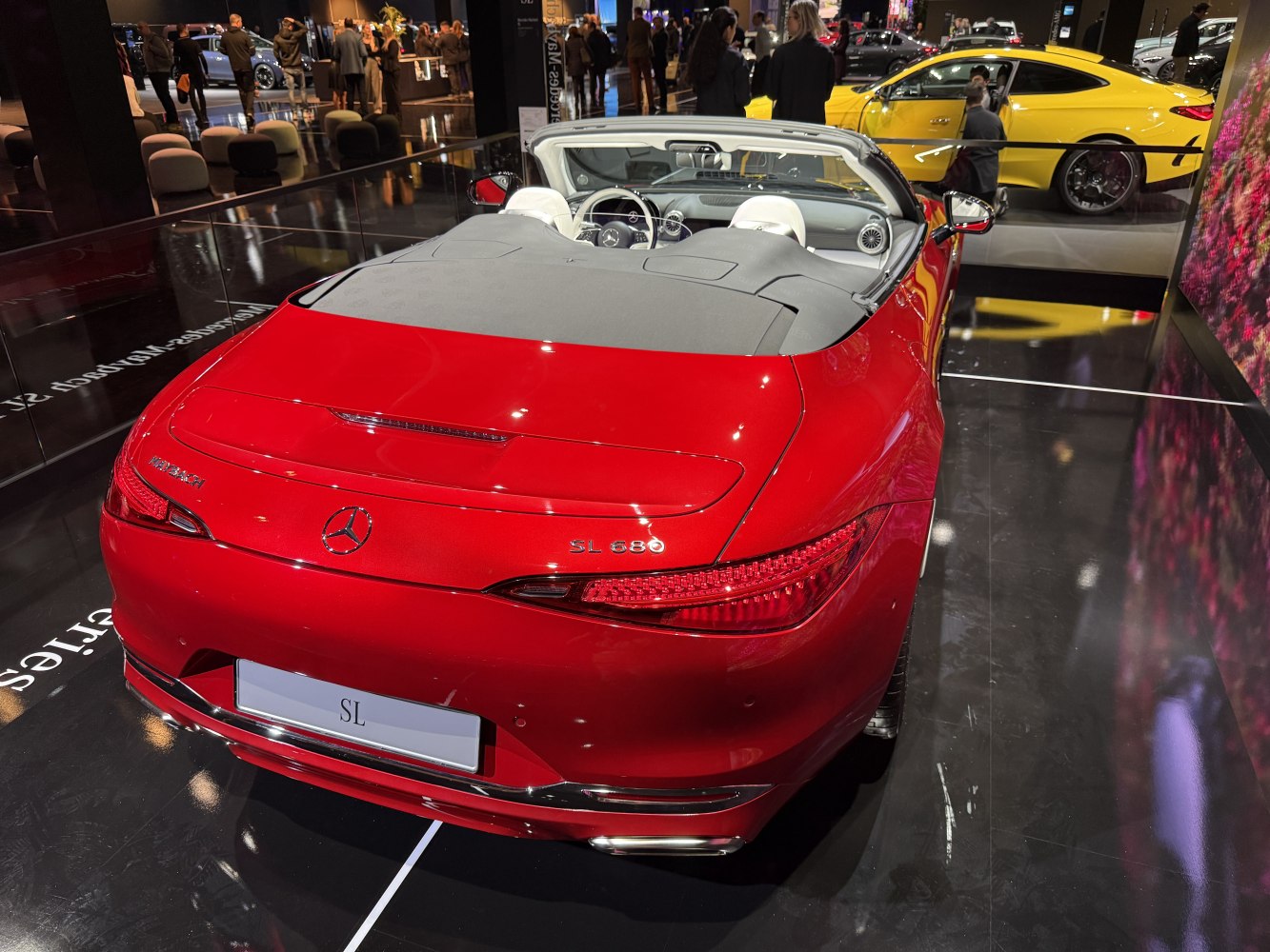 Rear view of a luxury red convertible with soft top and distinctive taillights.