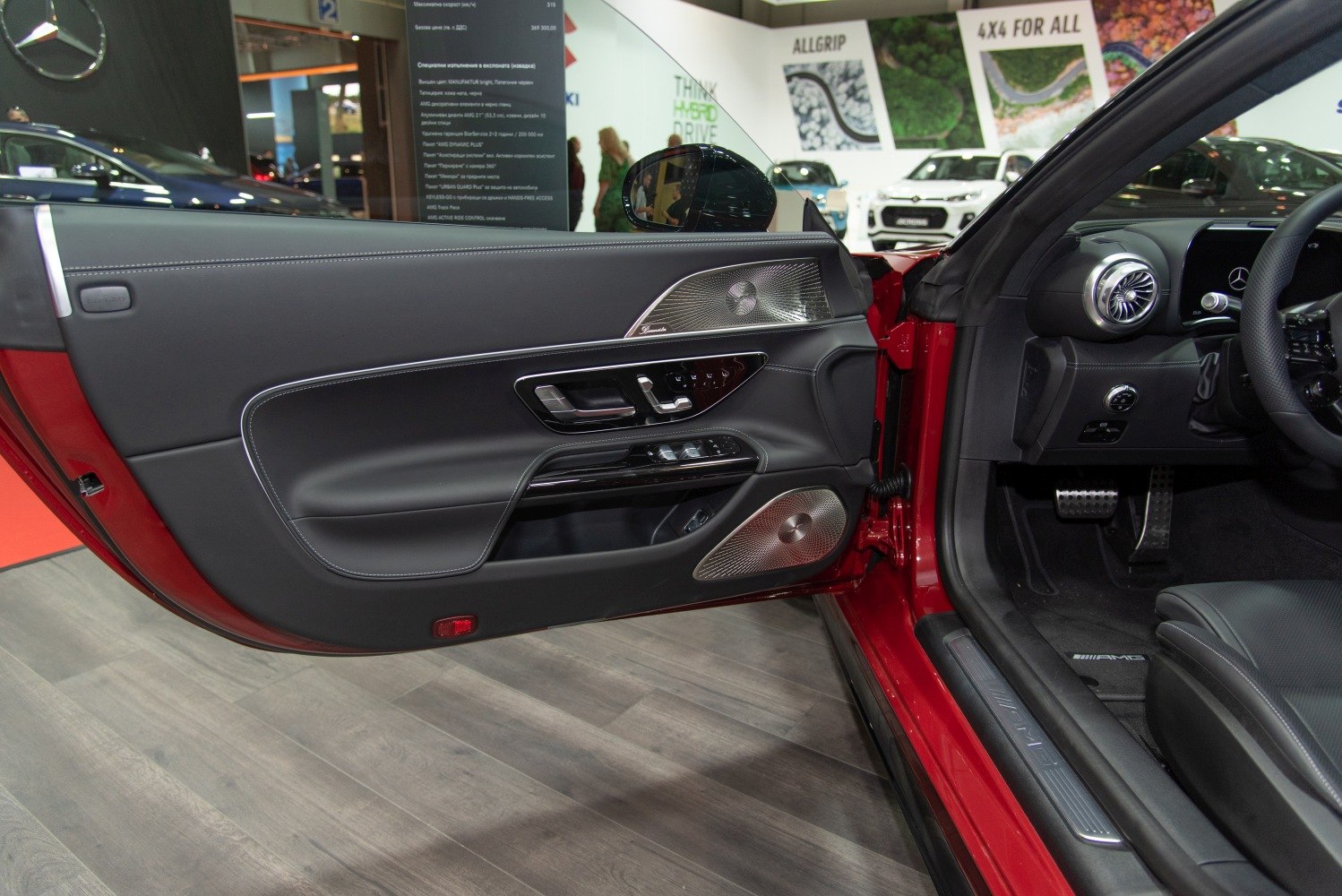 Luxury car door panel with chrome speaker grilles and AMG pedals