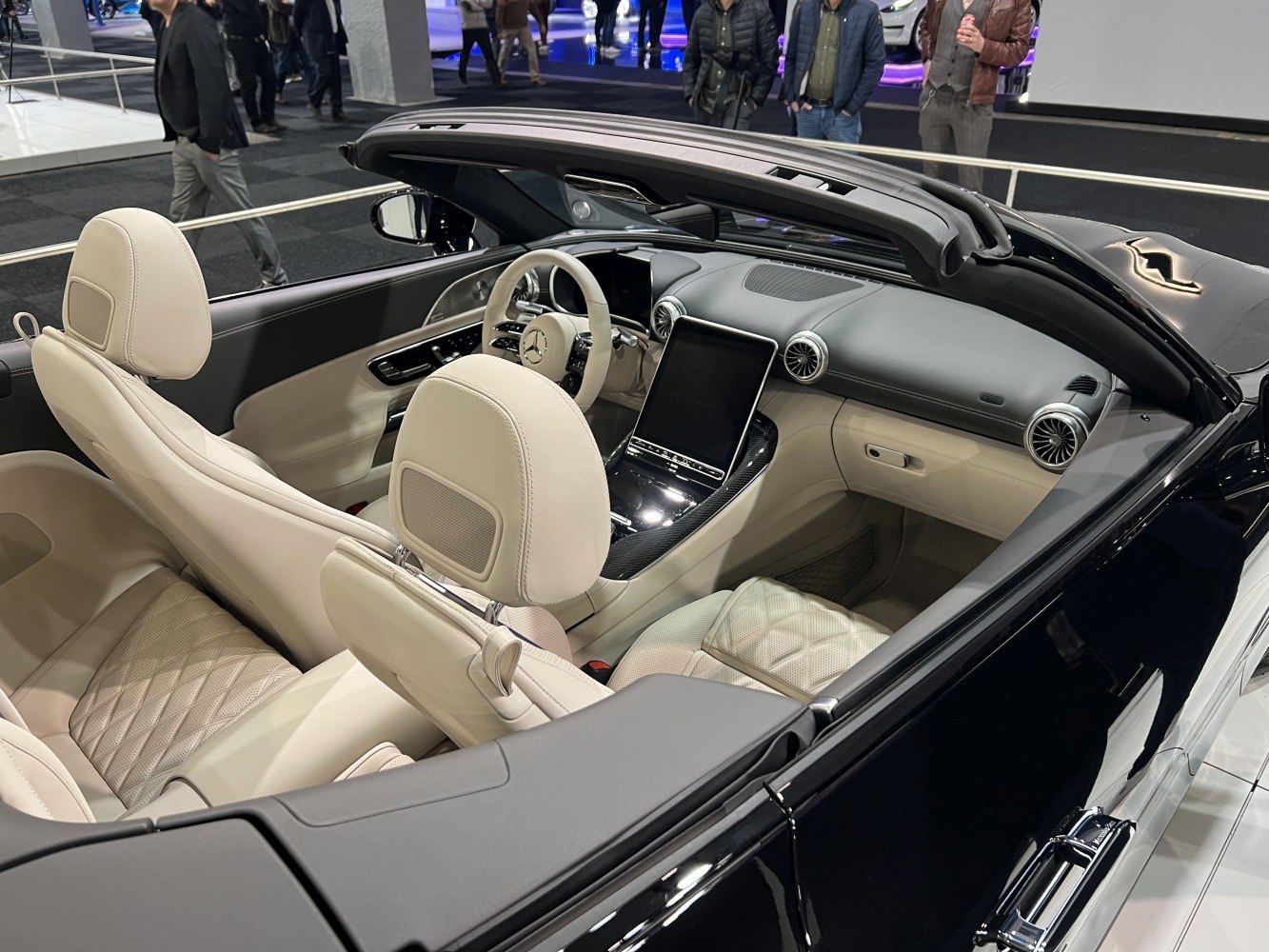 Beige leather seats and large digital touchscreen dashboard in a convertible interior