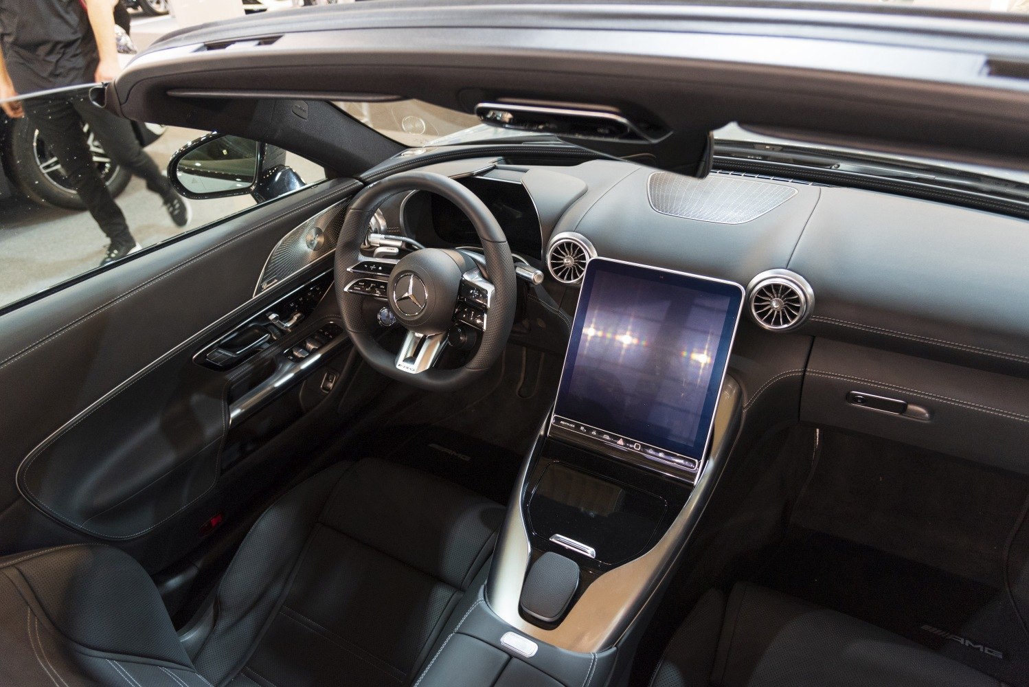 Modern car interior with large touchscreen, AMG steering wheel, and circular air vents