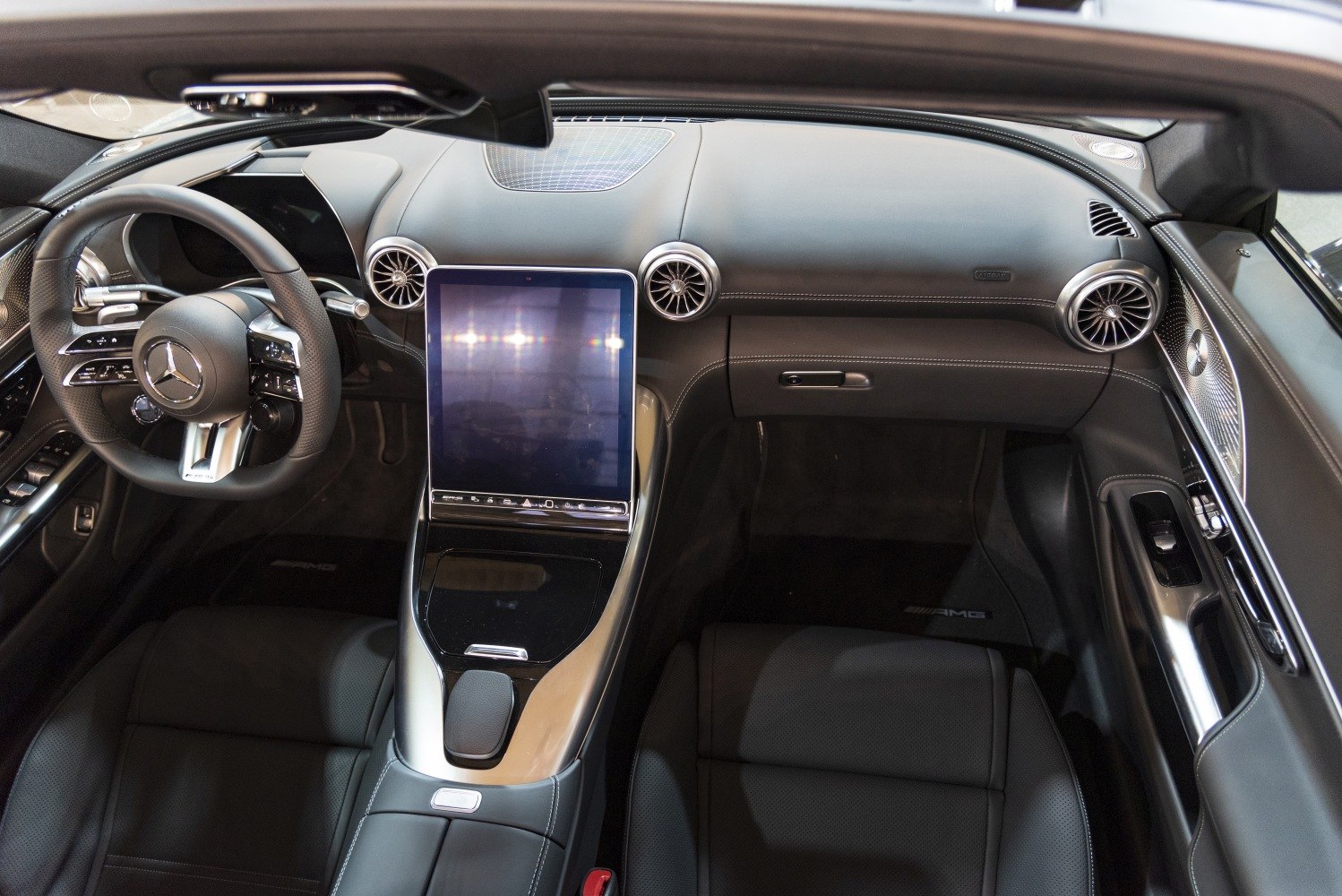 Large central touchscreen and sporty steering wheel in luxury car interior