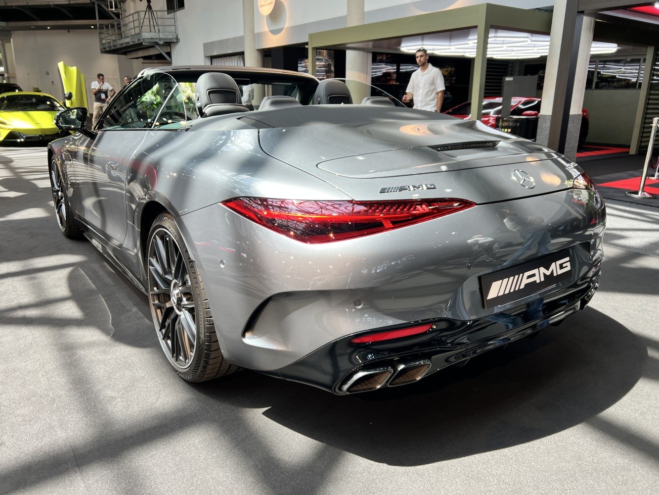 Rear view of a luxury AMG convertible roadster with distinct taillights and quad exhaust tips.