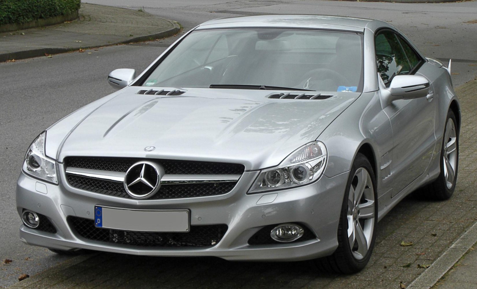 Silver luxury coupe with detailed headlights and grille in front view