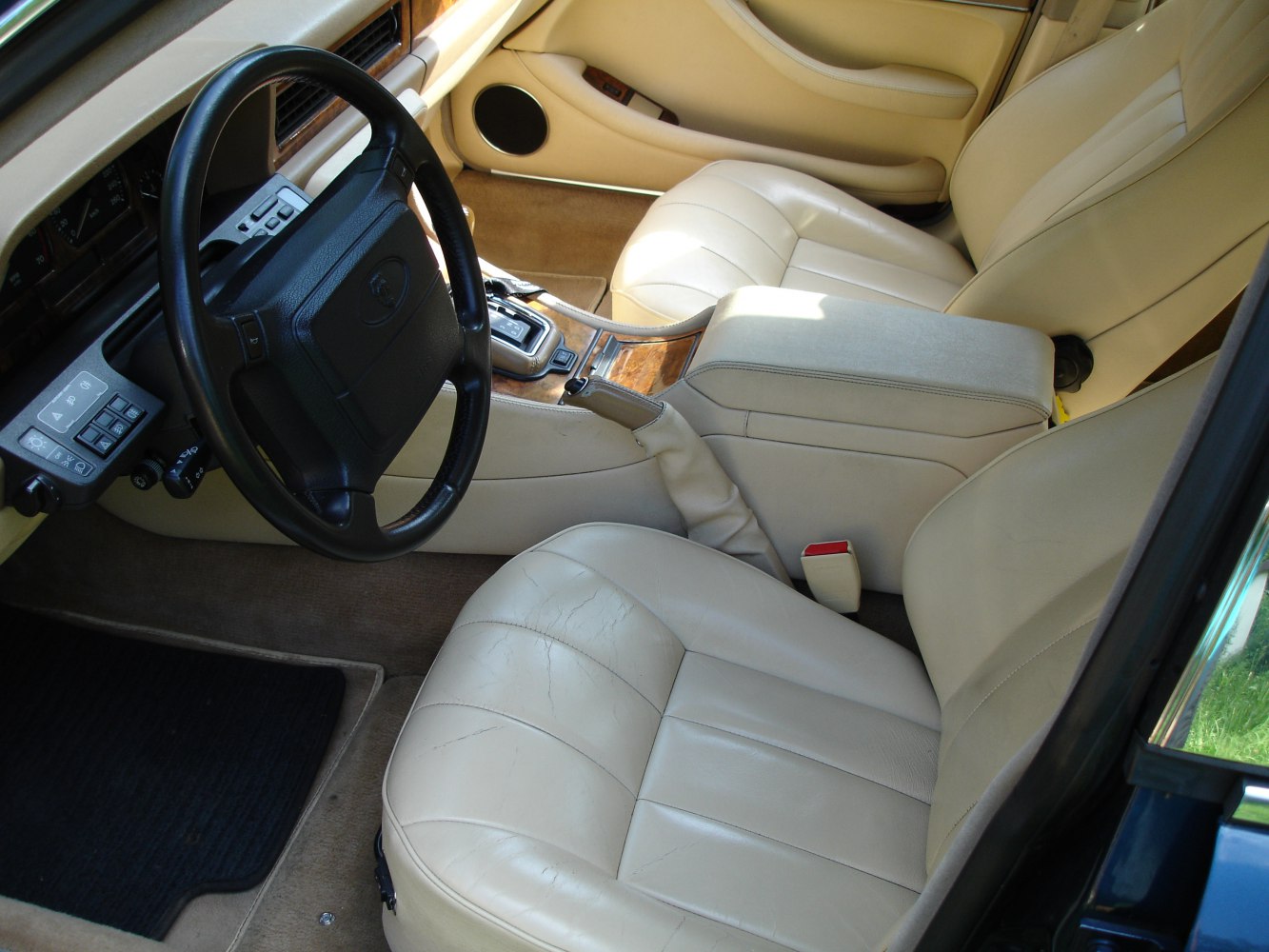 Beige leather seats and black steering wheel with wood-trimmed console
