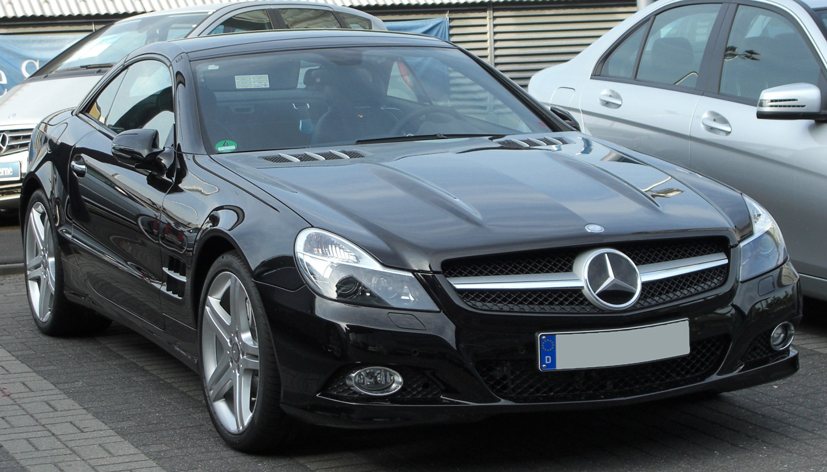 Front-angle view of a sleek black luxury sports coupe with distinctive hood vents and prominent grille.