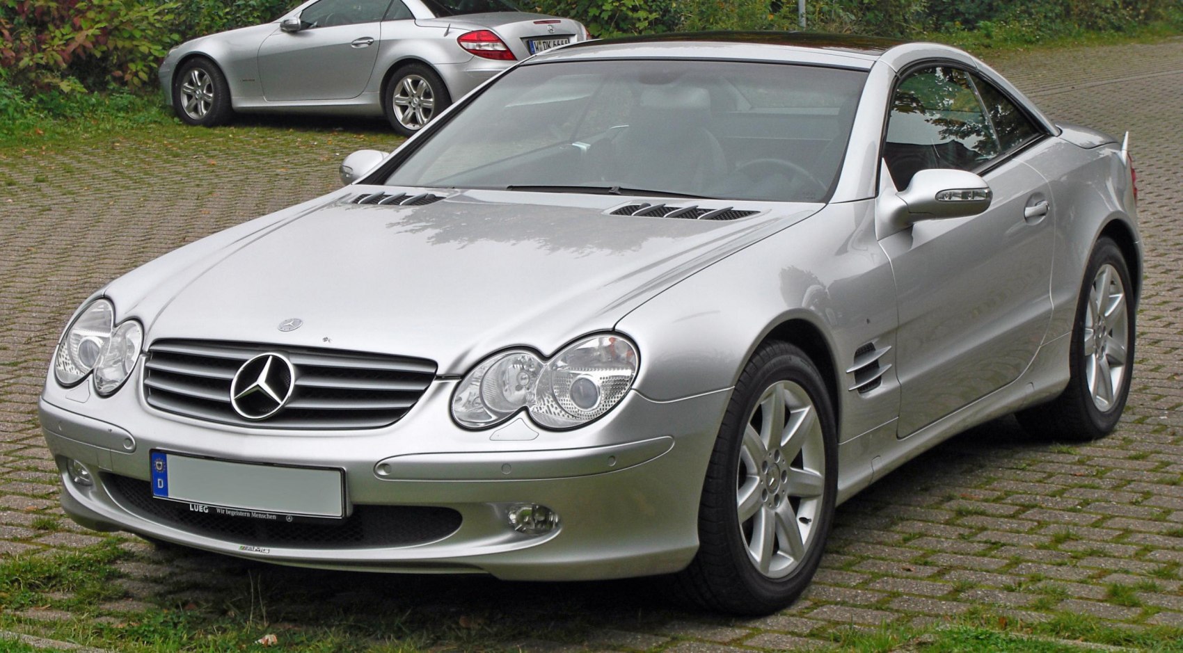 Front view of silver luxury coupe with twin headlights and hood vents