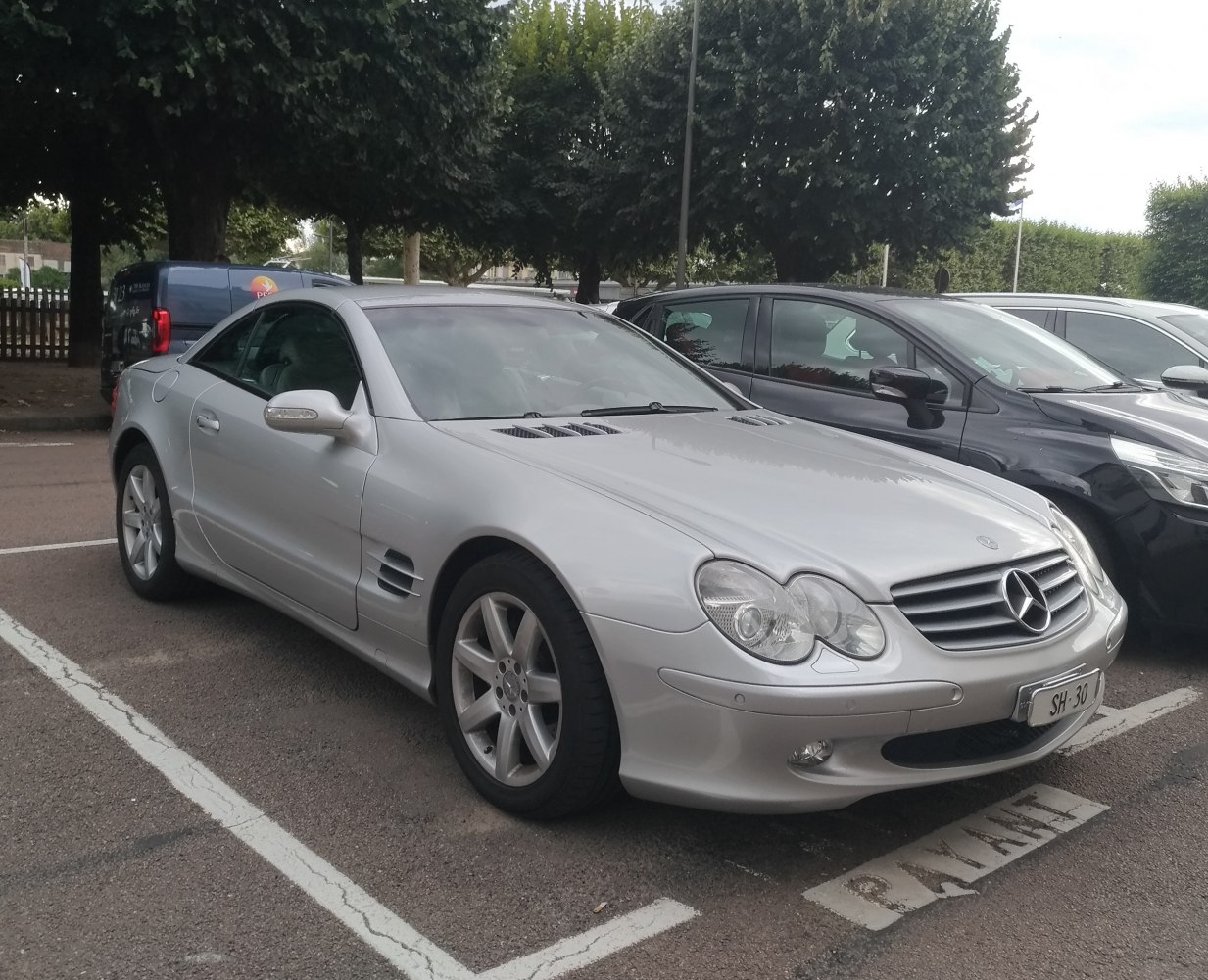 Sporty silver coupe with double round headlights, hood vents, and alloy wheels.