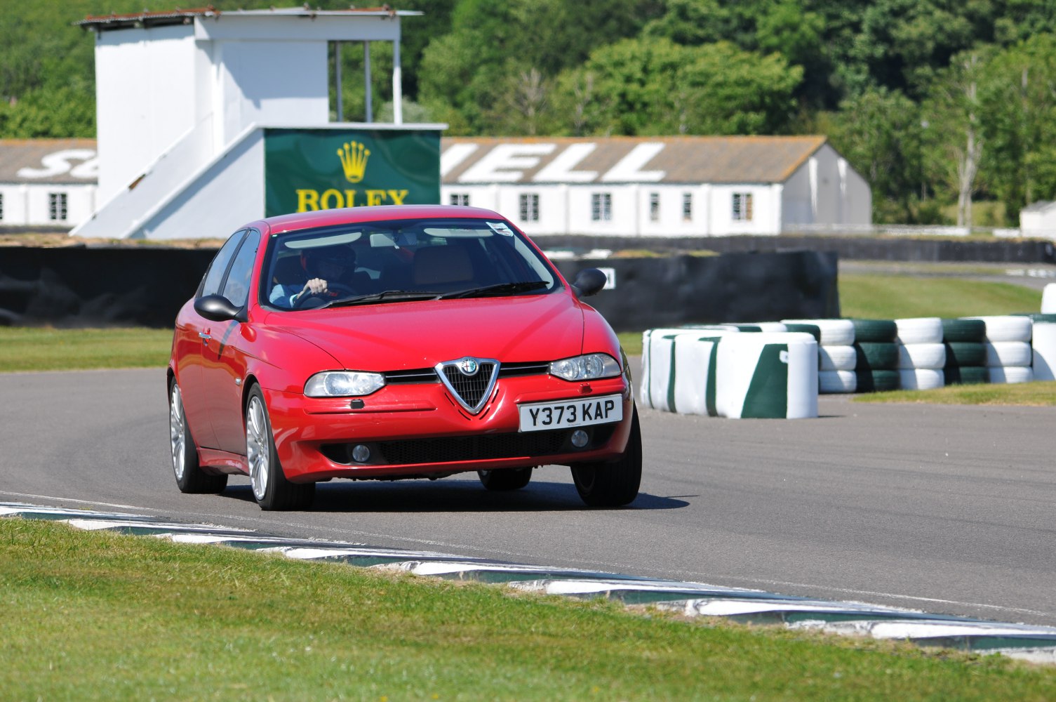 Red sedan with distinct Alfa Romeo front grille on race track corner
