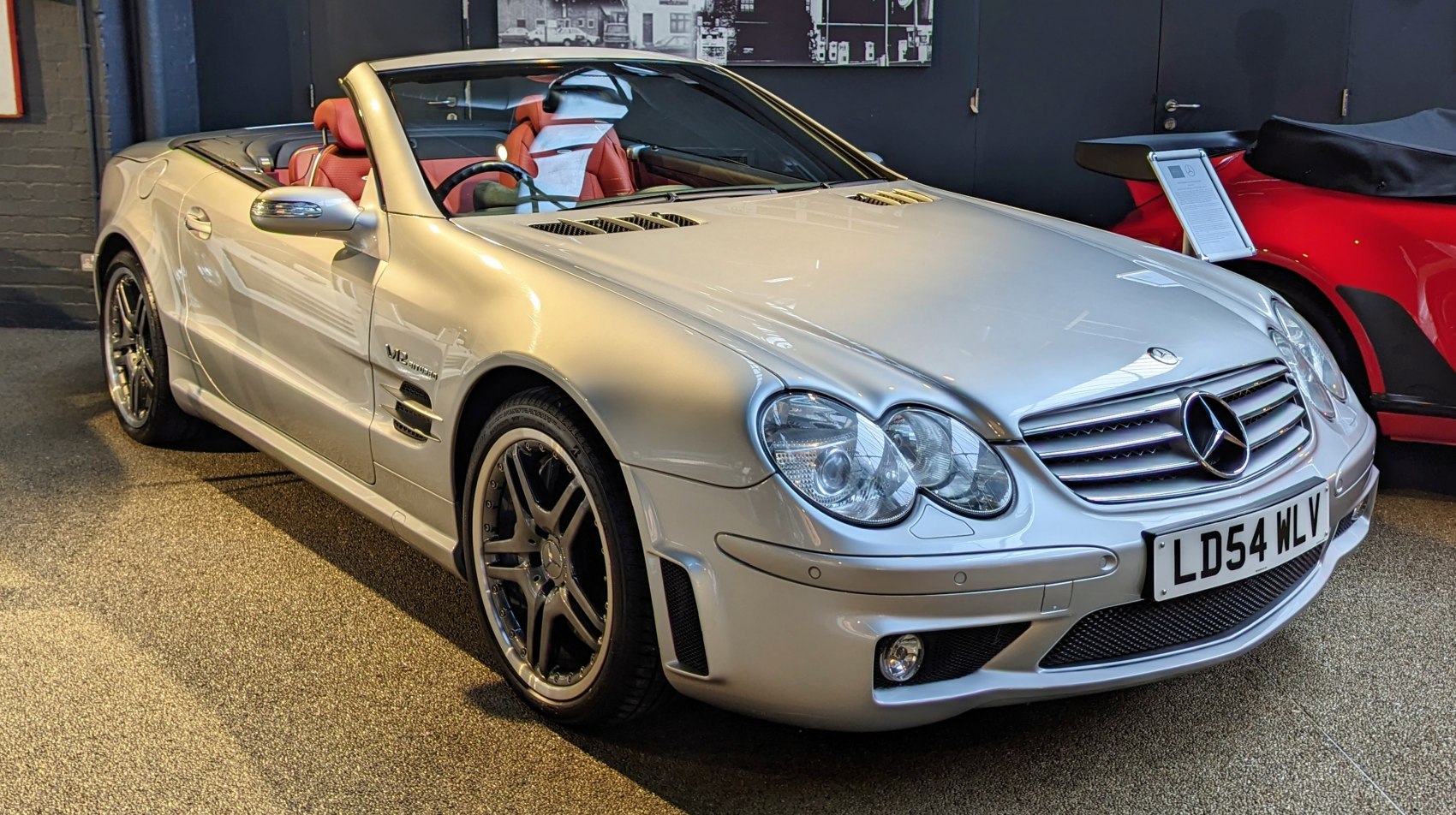 Silver convertible with V12 Biturbo badge, black rims, and red leather interior