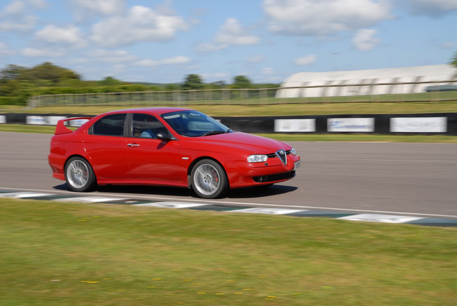 Red sedan with rear spoiler racing on track