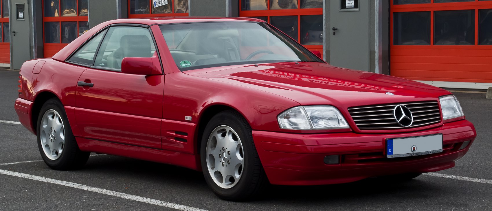 Red two-door coupe with front grille and alloy wheels