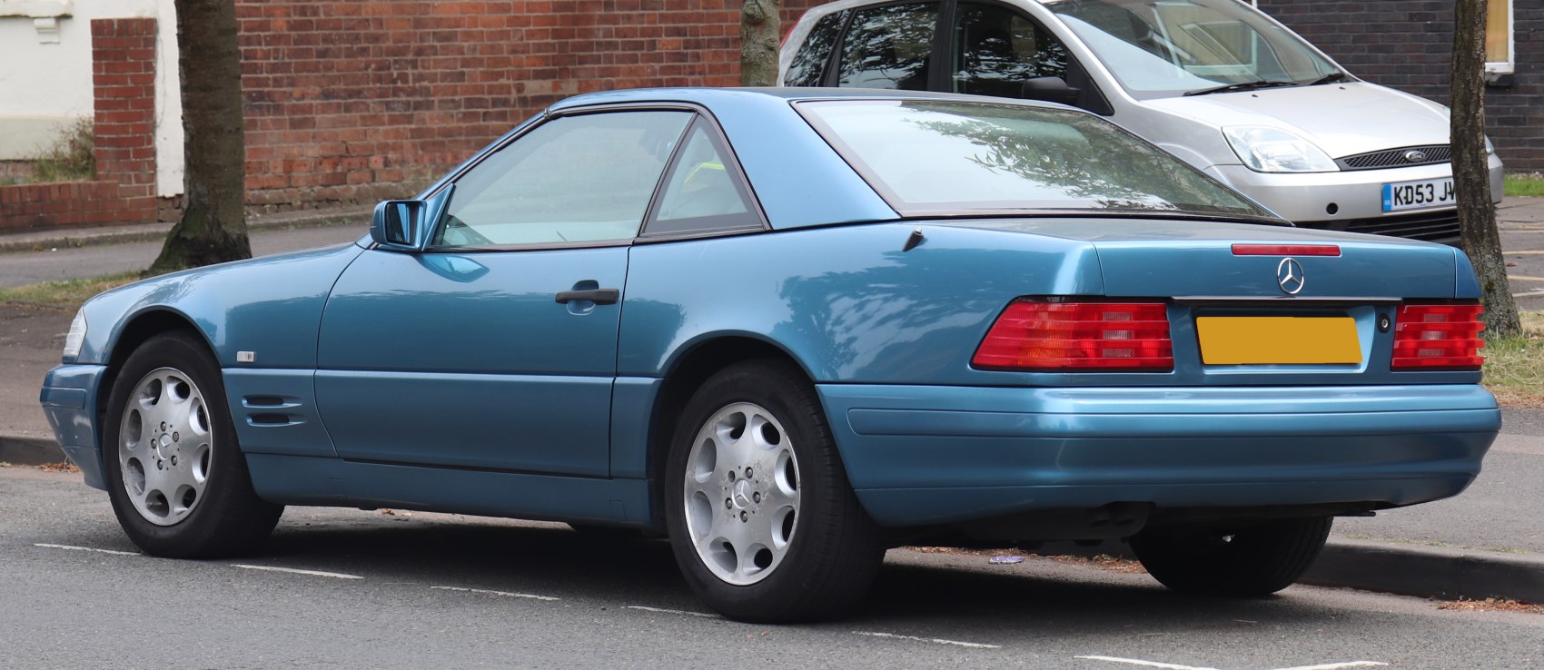Blue classic coupe rear side view with signature taillights and alloy wheels