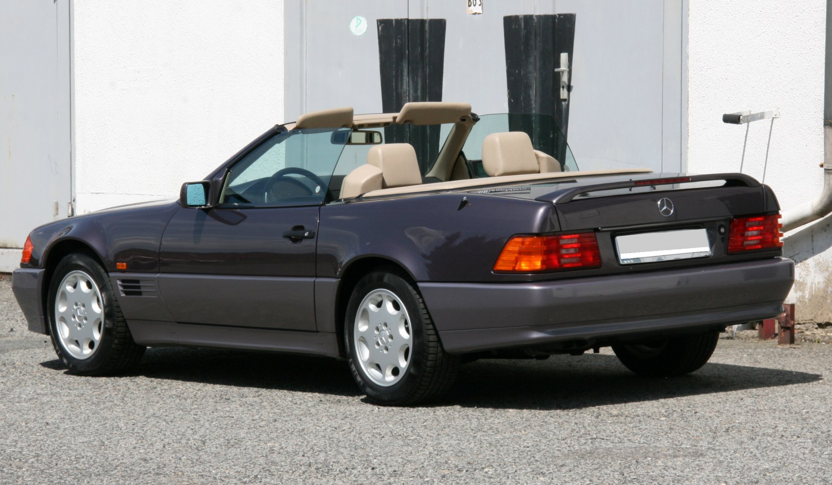 Convertible rear and side view showing tail lights, wheels, and beige interior