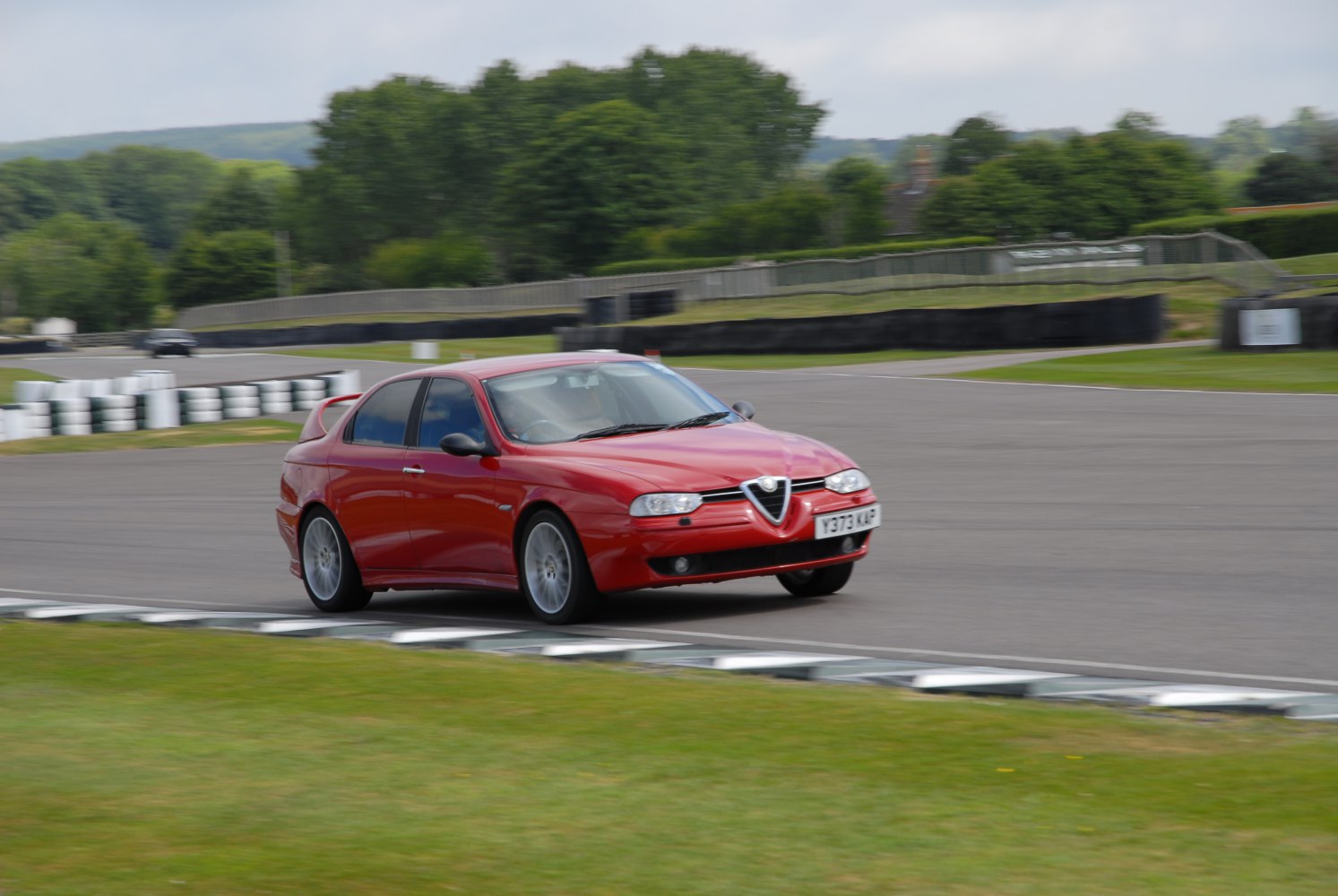 Red sports sedan maneuvering a race track corner