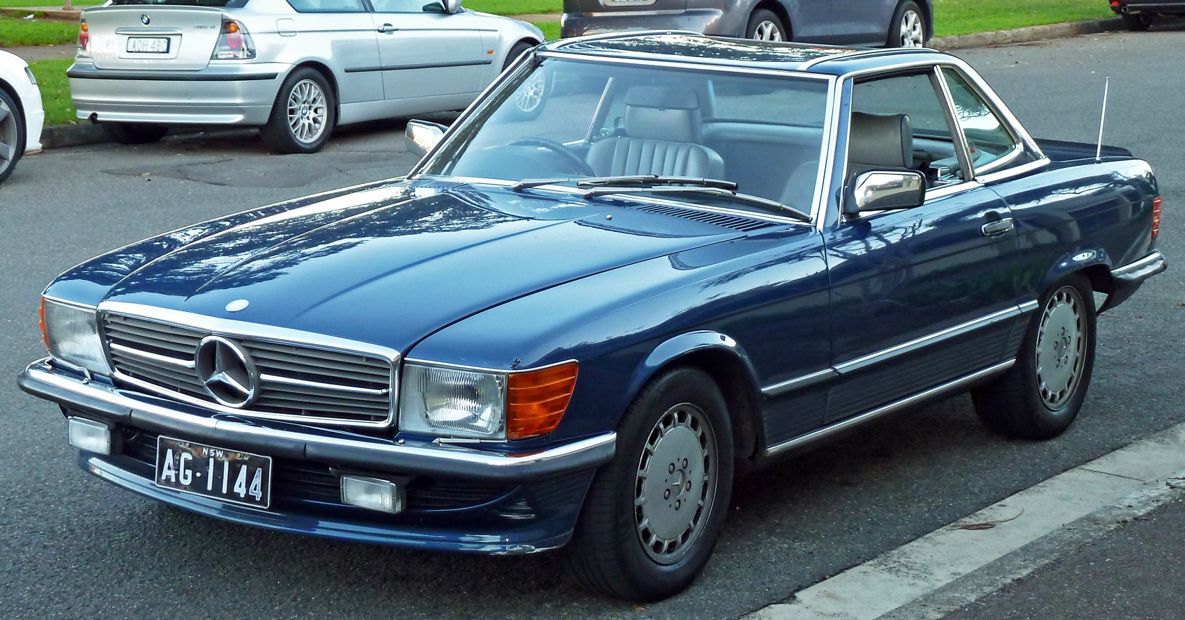Vintage blue coupe with chrome grille and trim, angular headlights, and sleek body lines