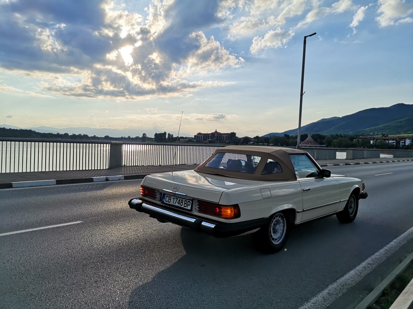 Classic vintage convertible roadster with soft top roof on a bridge.