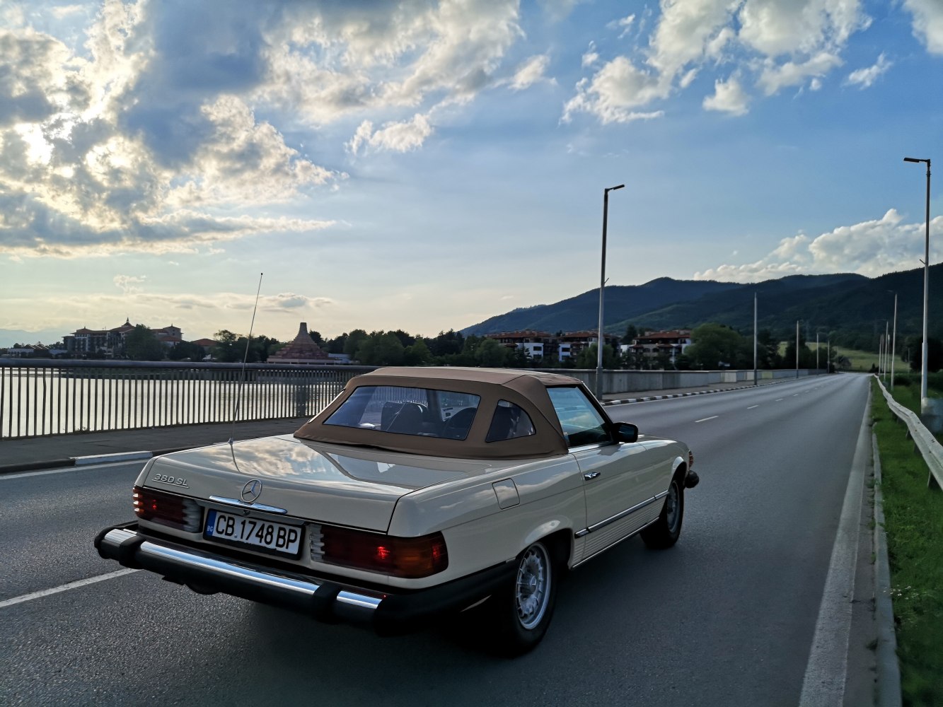 Rear view of classic beige soft-top convertible on open road