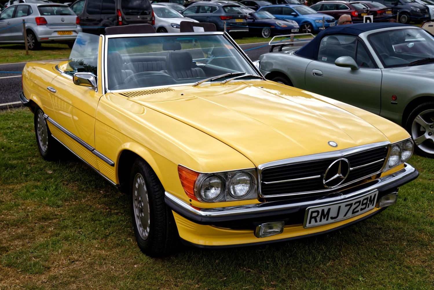 Yellow convertible with chrome grille and dual round headlights, classic roadster design