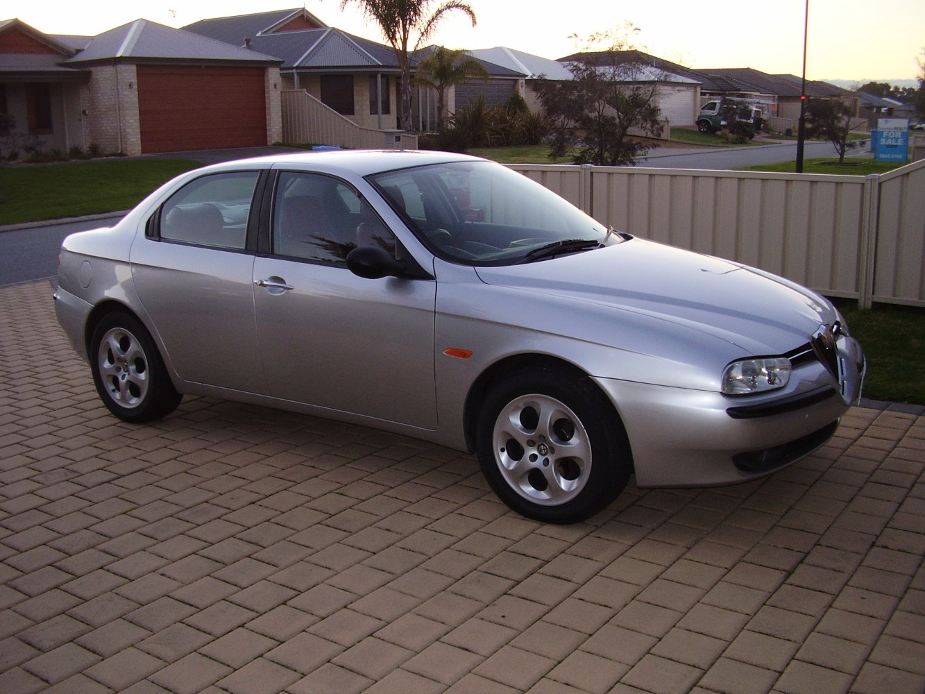 Silver four-door sedan with signature Alfa Romeo grille and alloy wheels