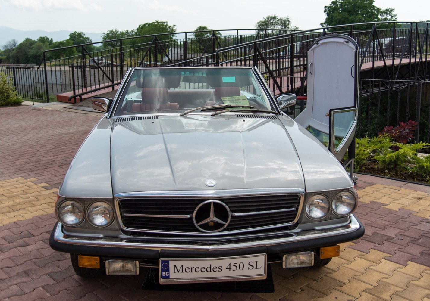 Front view of a vintage convertible with open driver's door and classic headlights