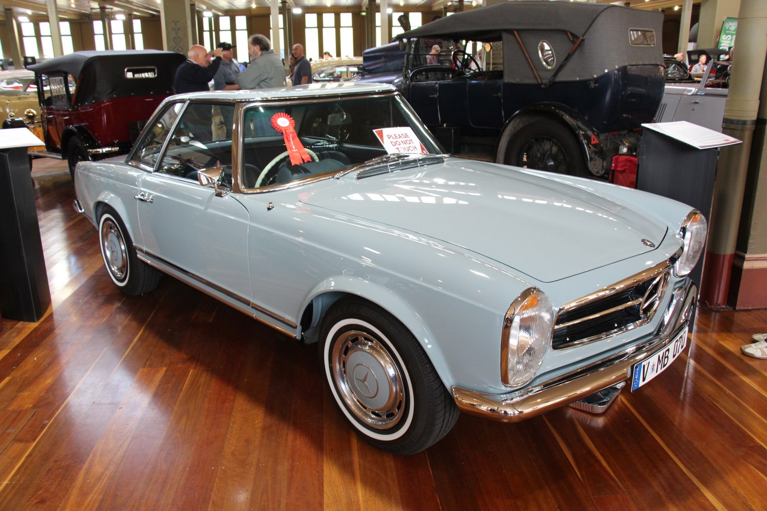 Vintage coupe with chrome accents and whitewall tires on polished wooden floor