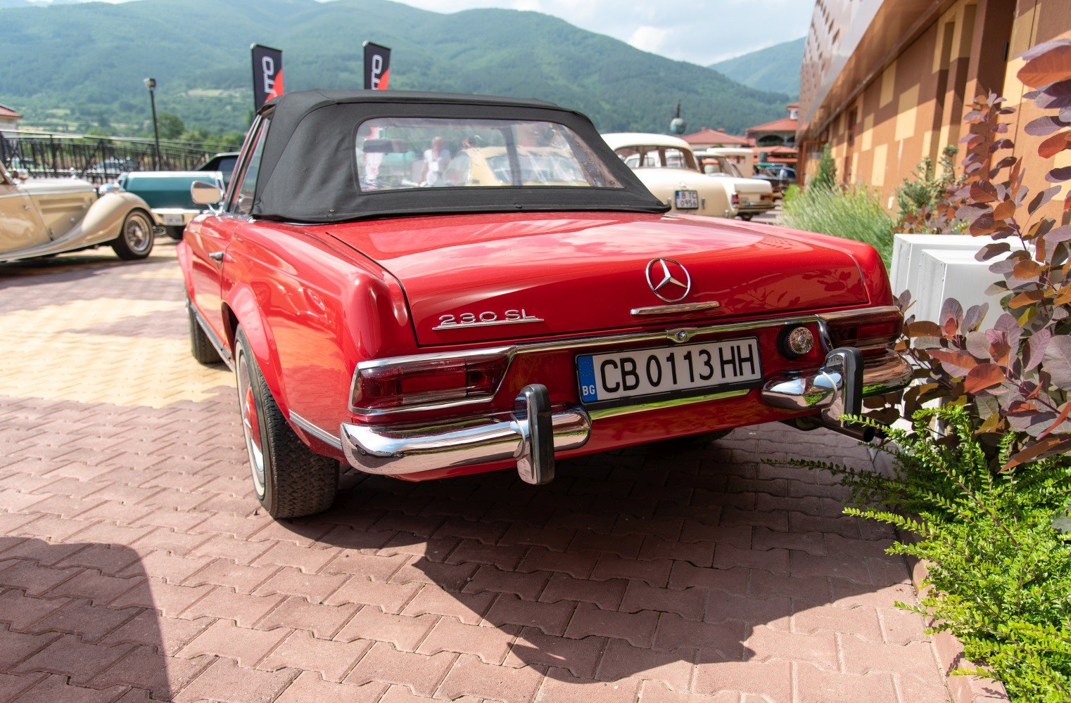 Rear view of a classic red convertible with chrome bumper and soft top roof