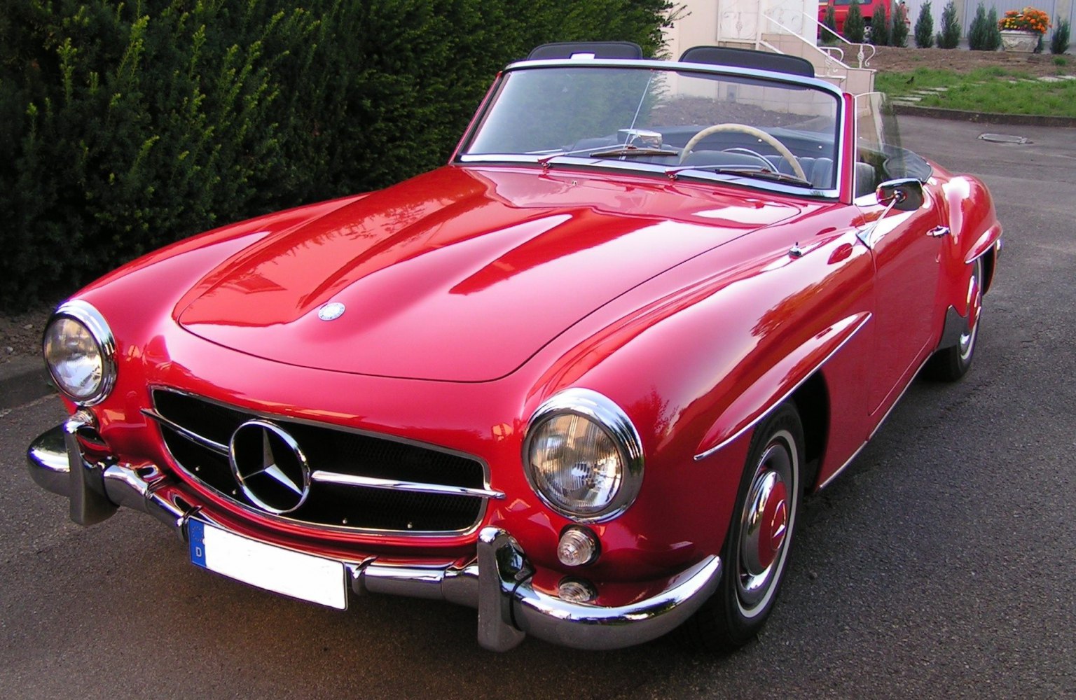 Glossy red vintage convertible with rounded headlights and chrome bumper