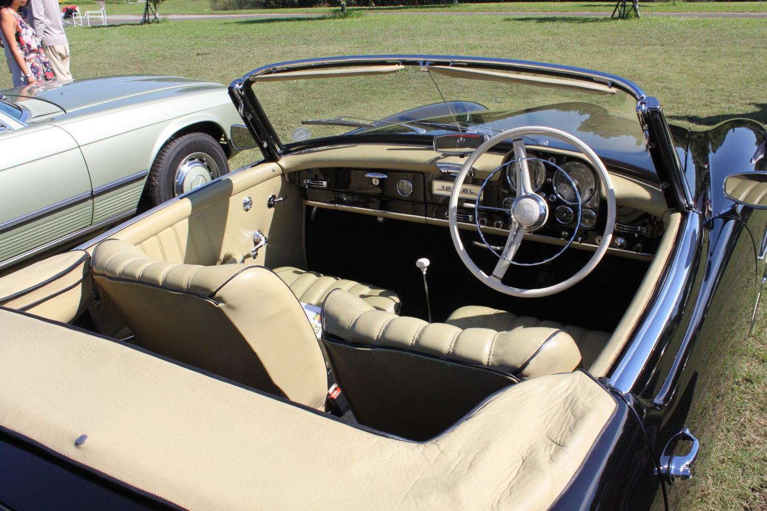 Convertible vintage car interior with cream leather seats and classic dashboard.