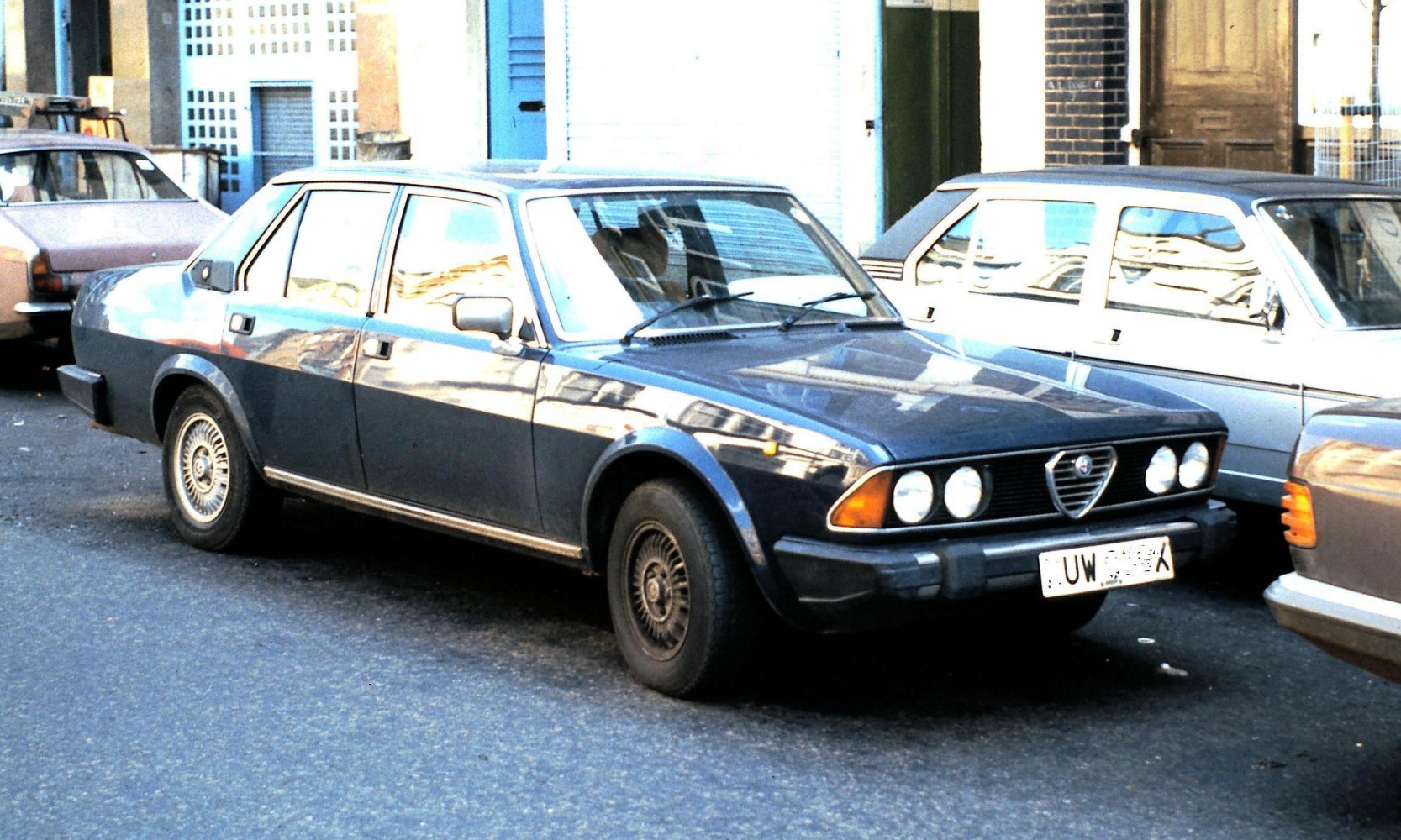 Front-side view of a sedan with quad headlights and vintage wheels