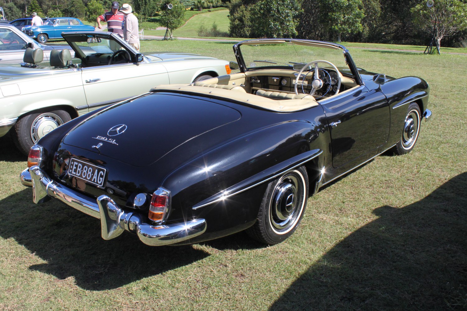 Glossy black vintage convertible roadster with chrome bumpers and white interior