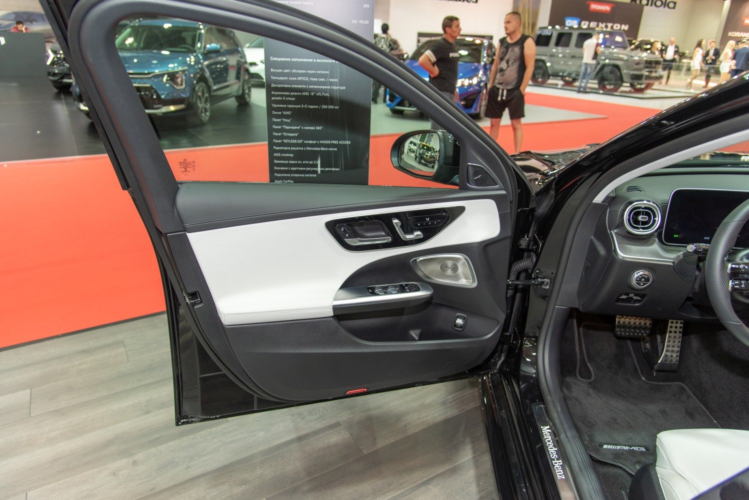 Close-up of a luxury car's driver side door panel with controls and materials.
