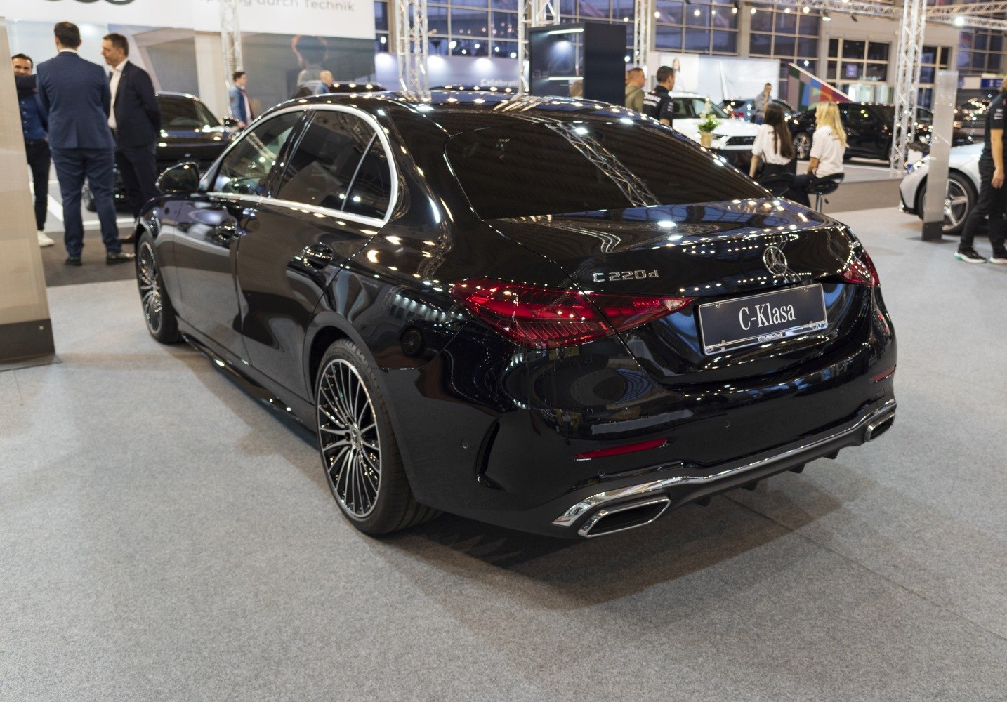 Black luxury sedan rear with LED tail lights and dual exhausts.