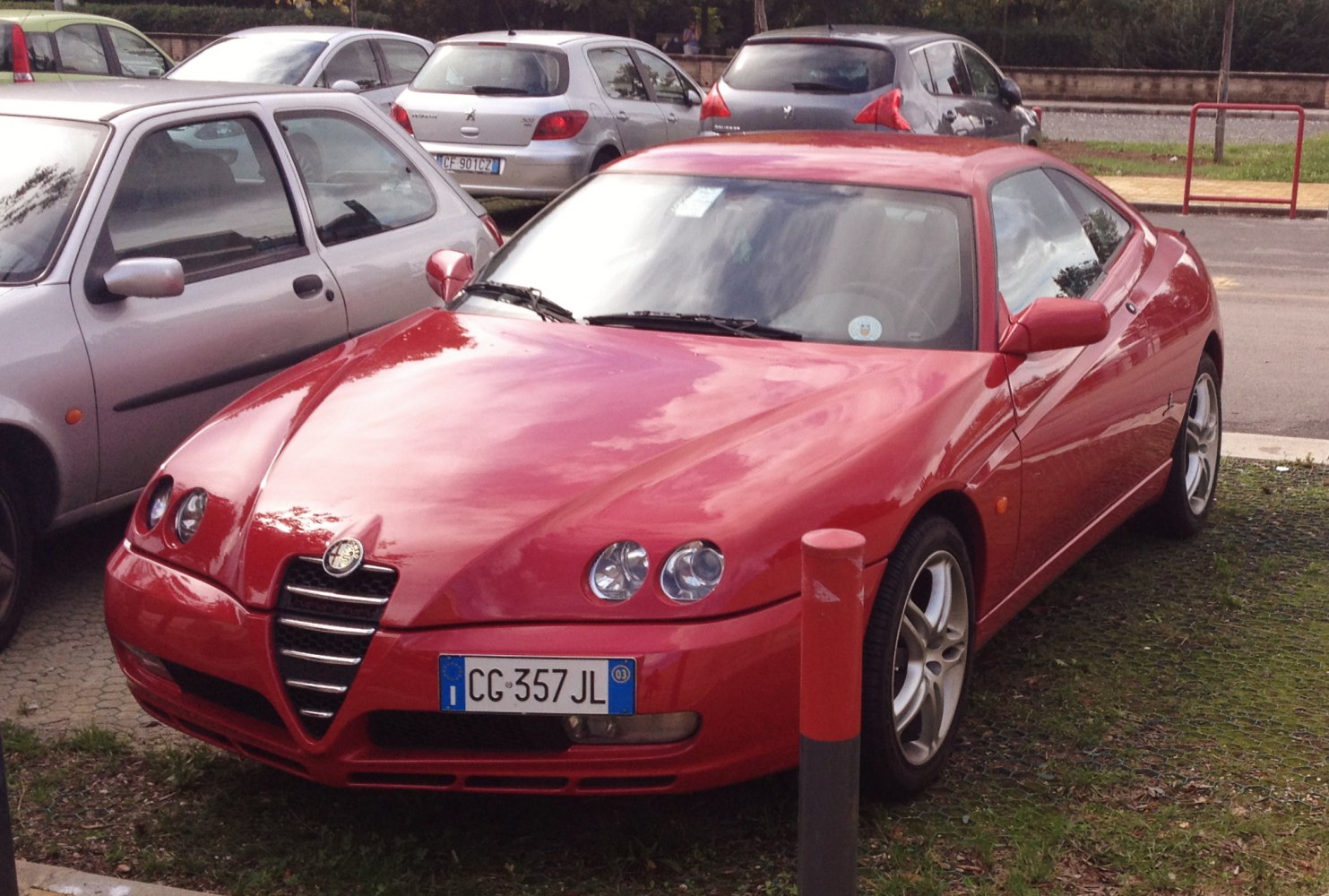 Red coupe with dual round headlights and distinctive front grille