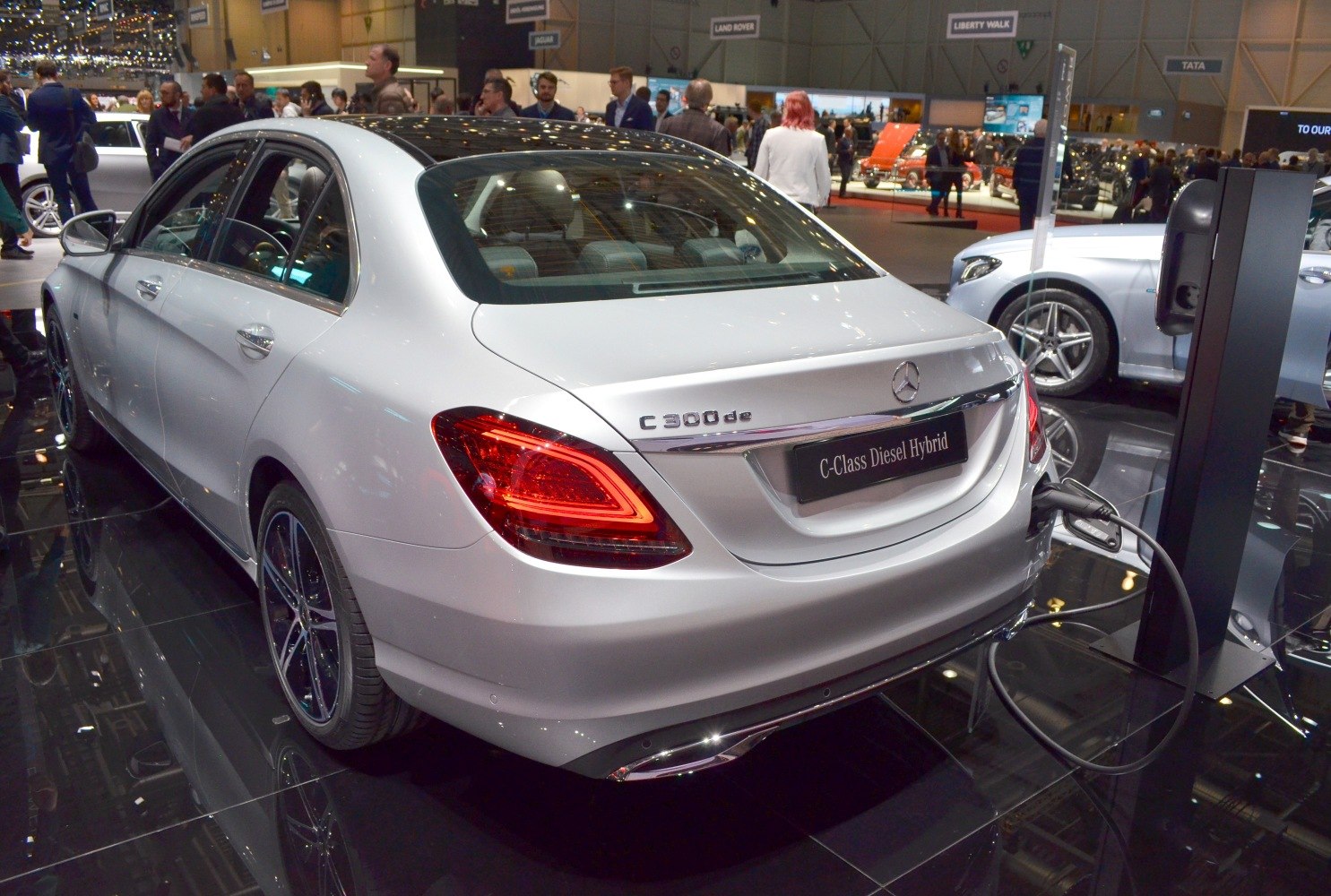 Rear view of a white sedan with tail lights and EV charging plug connected